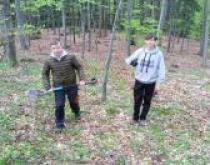 Dwóch uczniów z łopatą w lesie